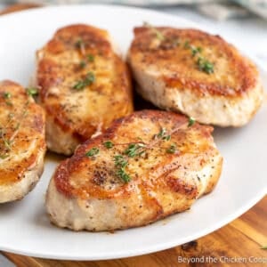 Four boneless pork chops on a white plate.