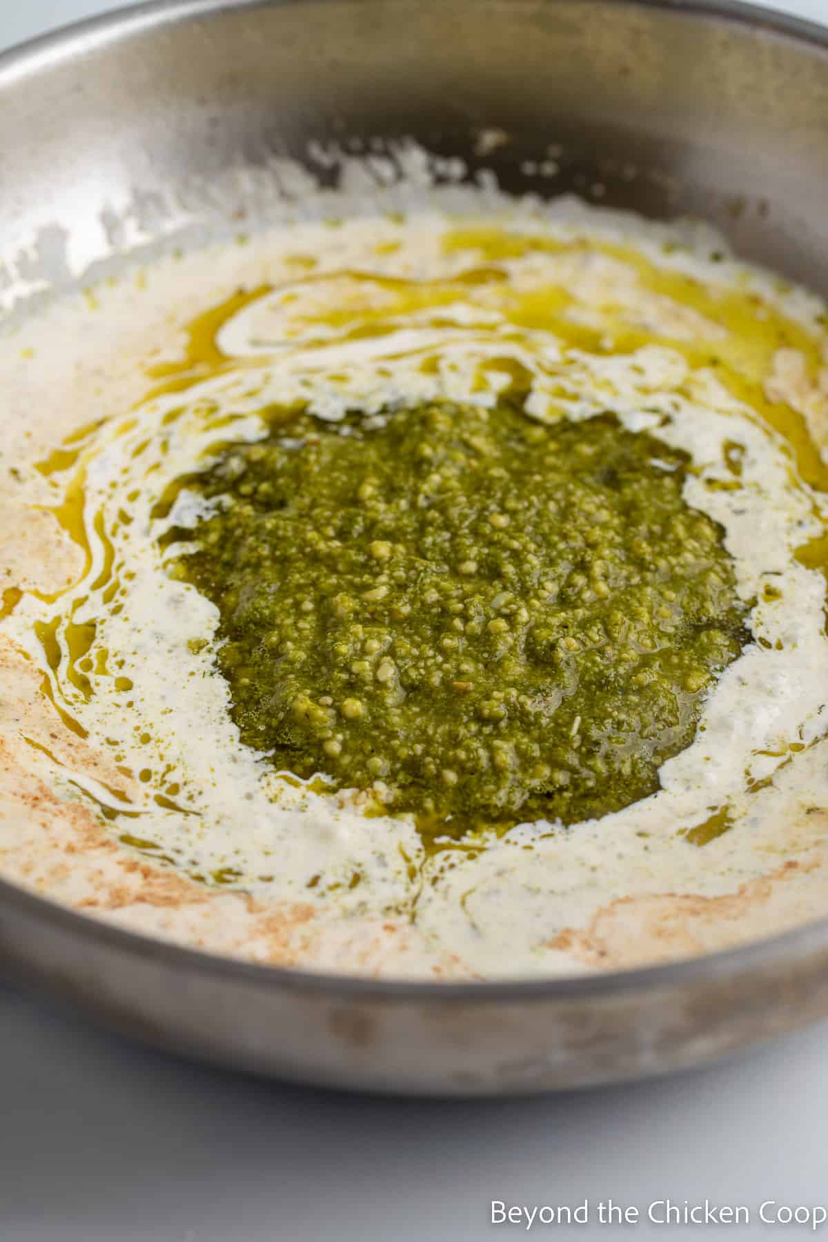 Pesto in a saucepan filled with cream. 