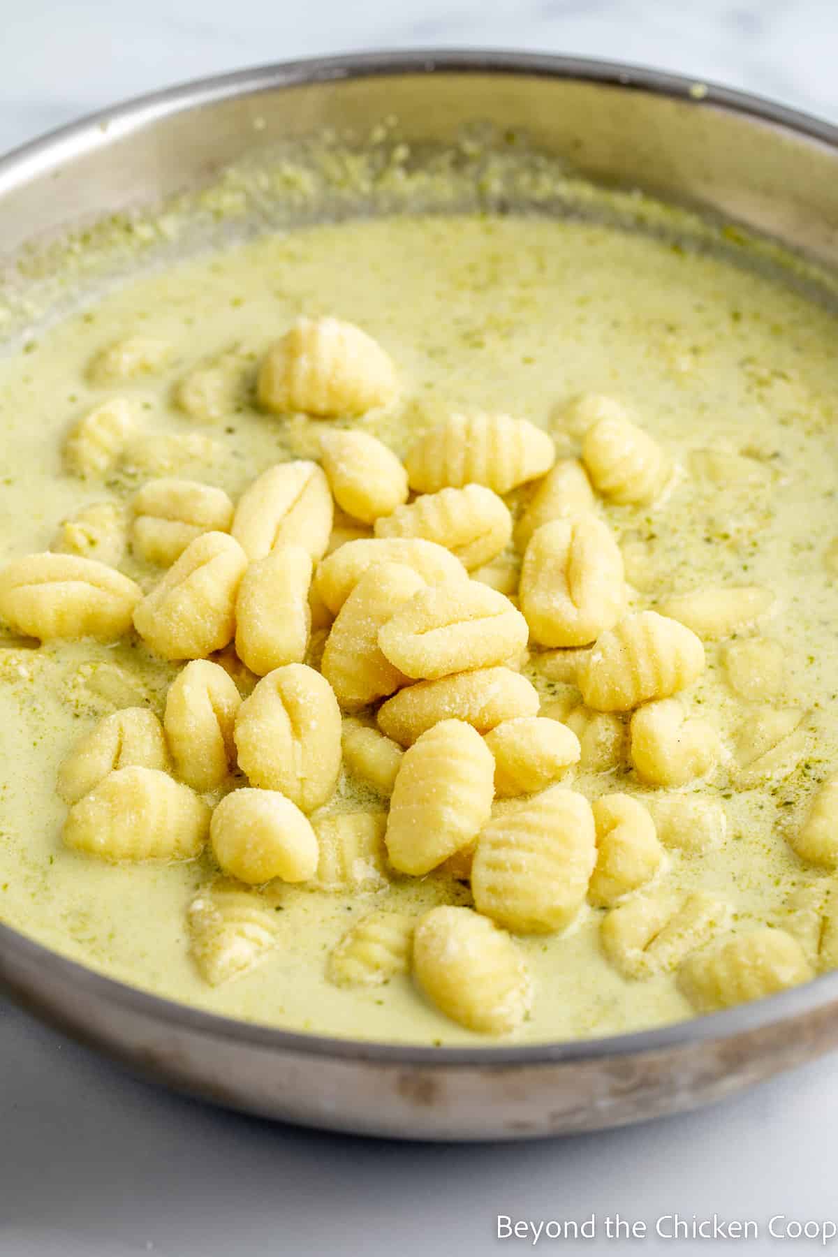 Gnocchi added to a cream sauce in a pan.