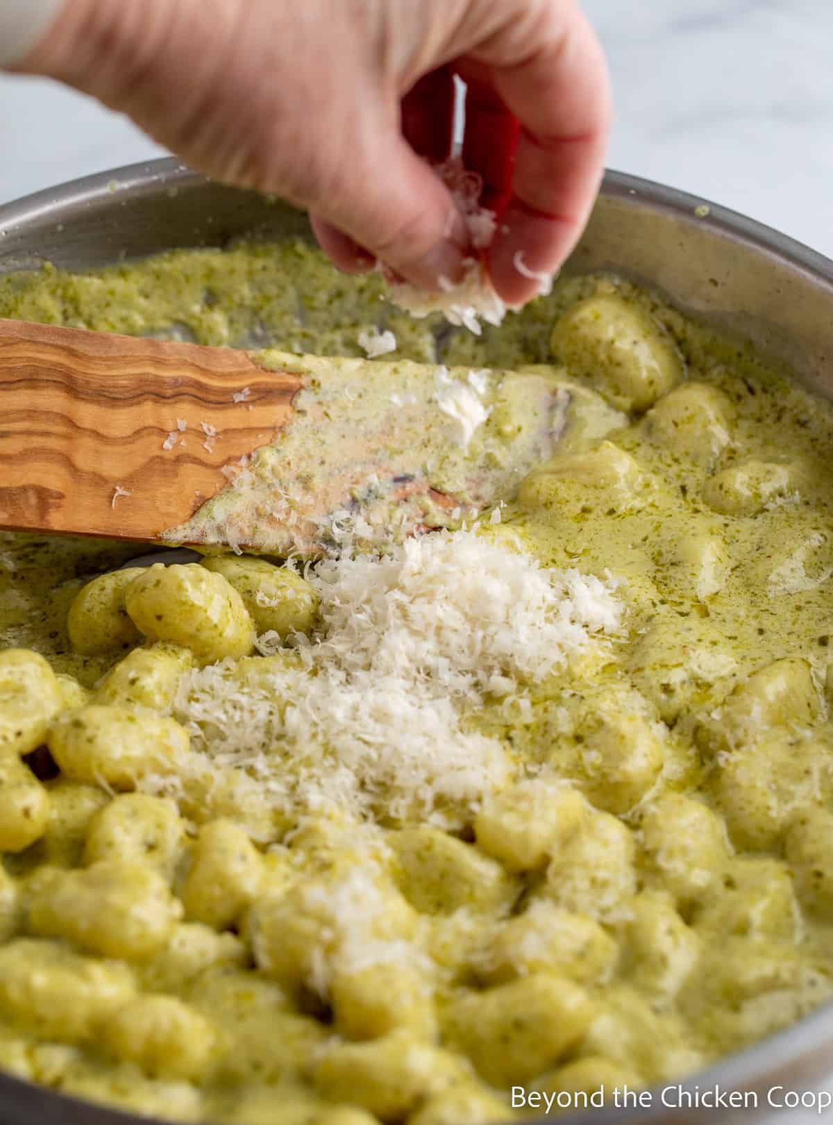 Sprinkling parmesan cheese over gnocchi in a pan. 