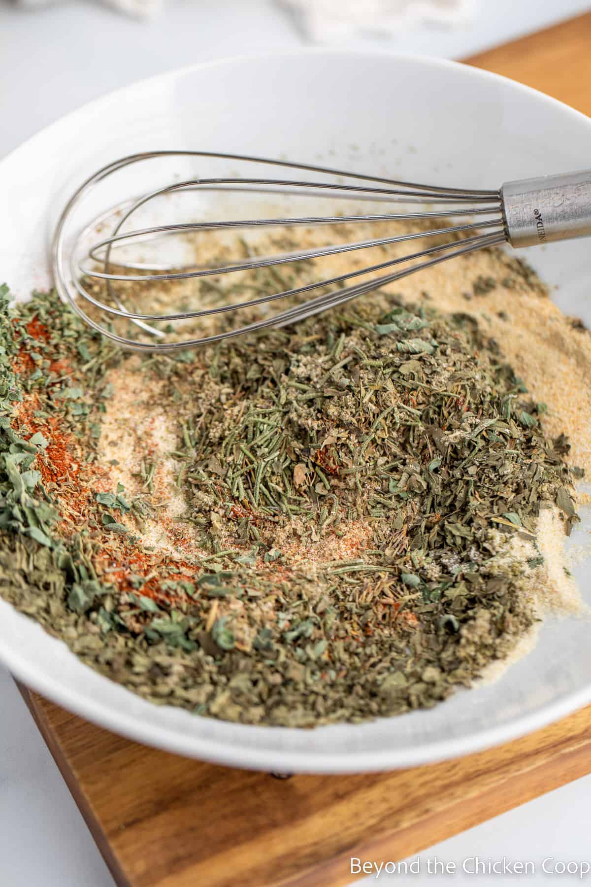 Mixing spices together in a bowl with a whisk. 