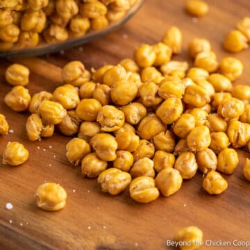A wooden board covered with roasted chickpeas.