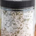 A glass jar filled with salt and minced rosemary.