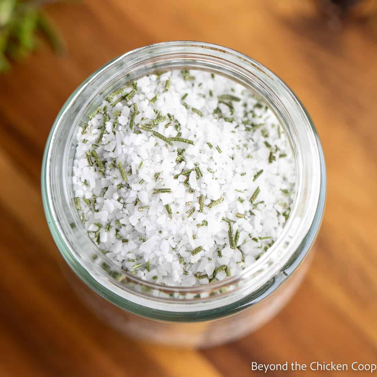 A jar filled with coarse salt and dried rosemary. 