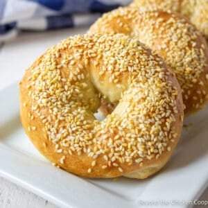 Sesame seed bagels on a white platter.