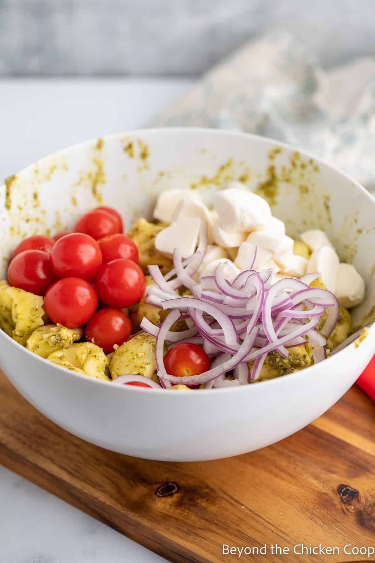 A bowl with pasta, tomatoes, cheese and onions. 