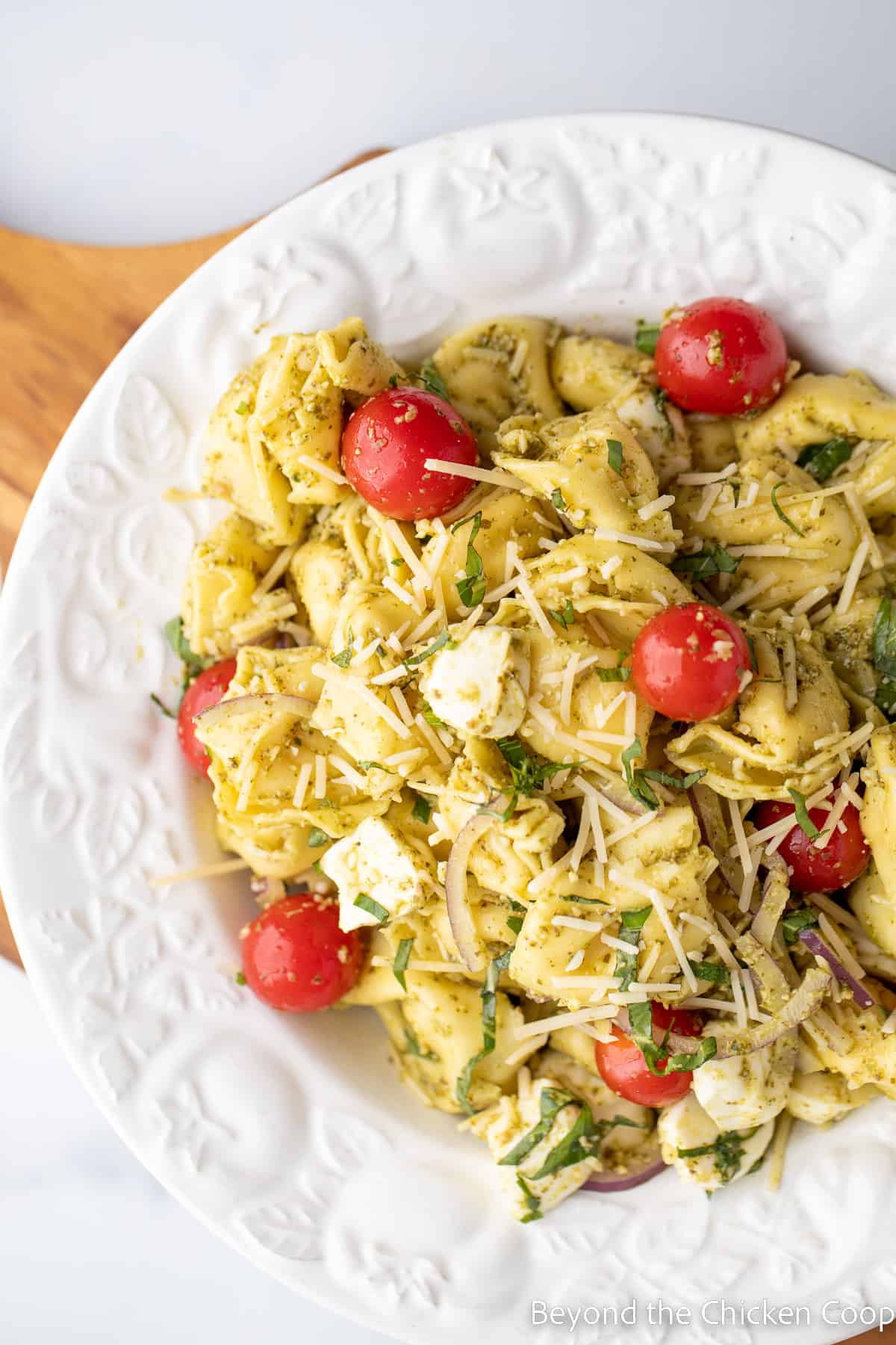 A white bowl filled with tortellini, tomatoes and mini mozzarella balls.