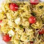 A pasta salad with pesto, tomatoes and cheese.