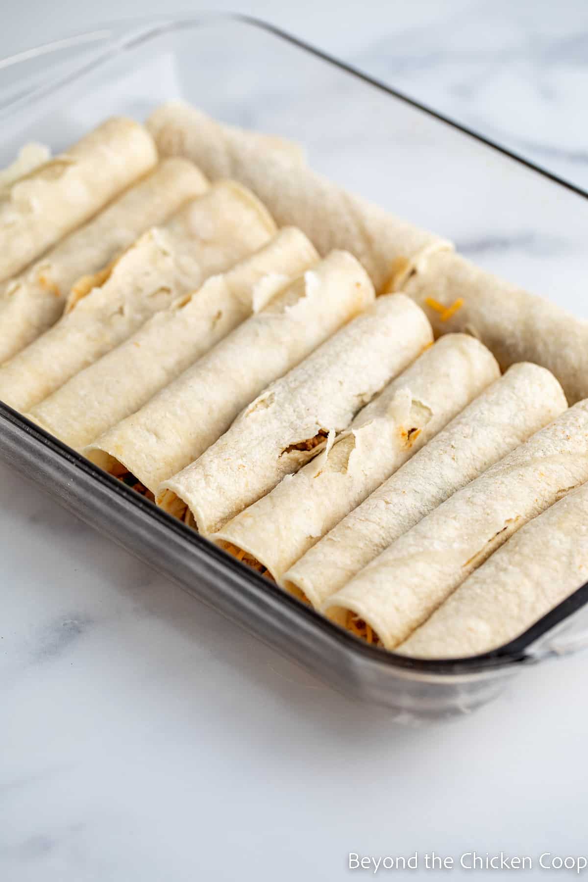 Rolled enchiladas in a baking dish.