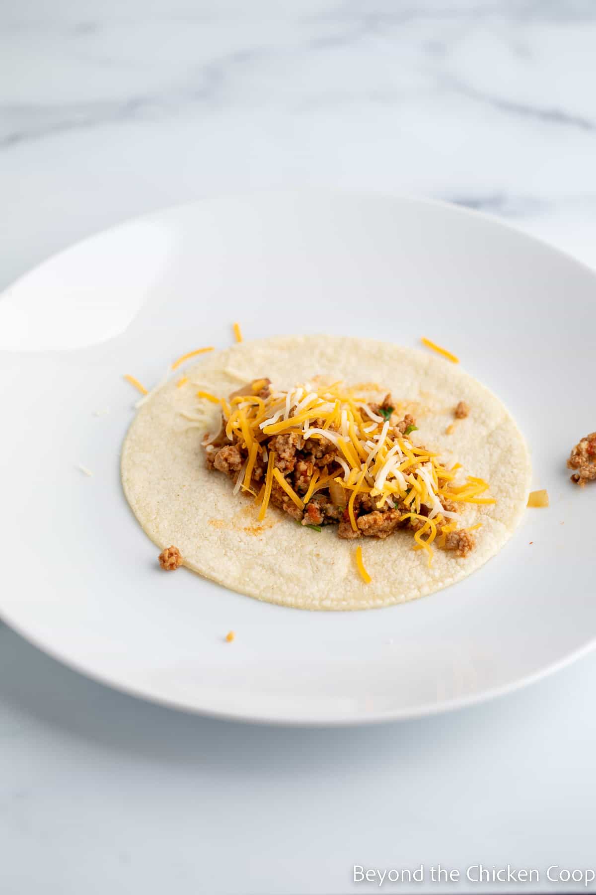 Meat filling and cheese on a tortilla.