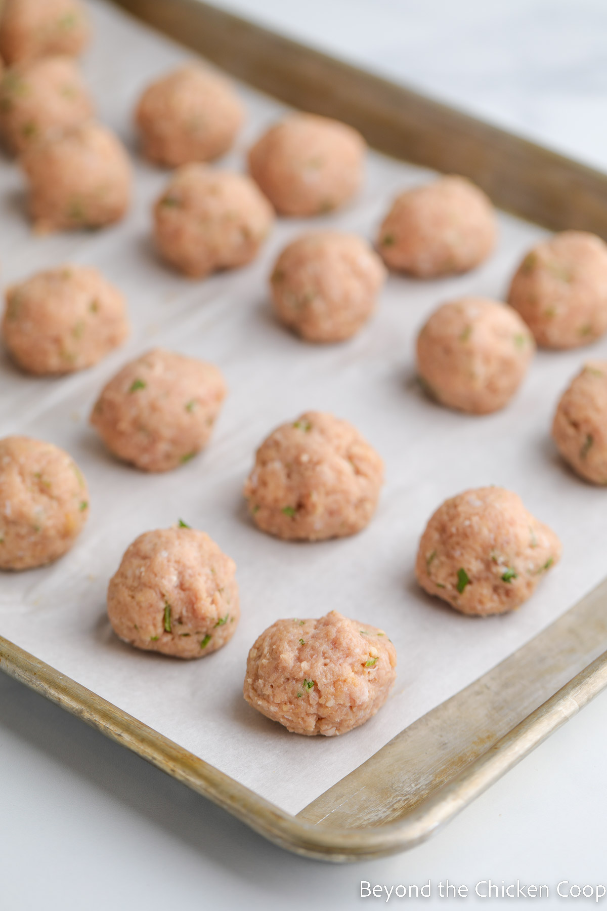 Unbaked meatballs on a baking sheet. 