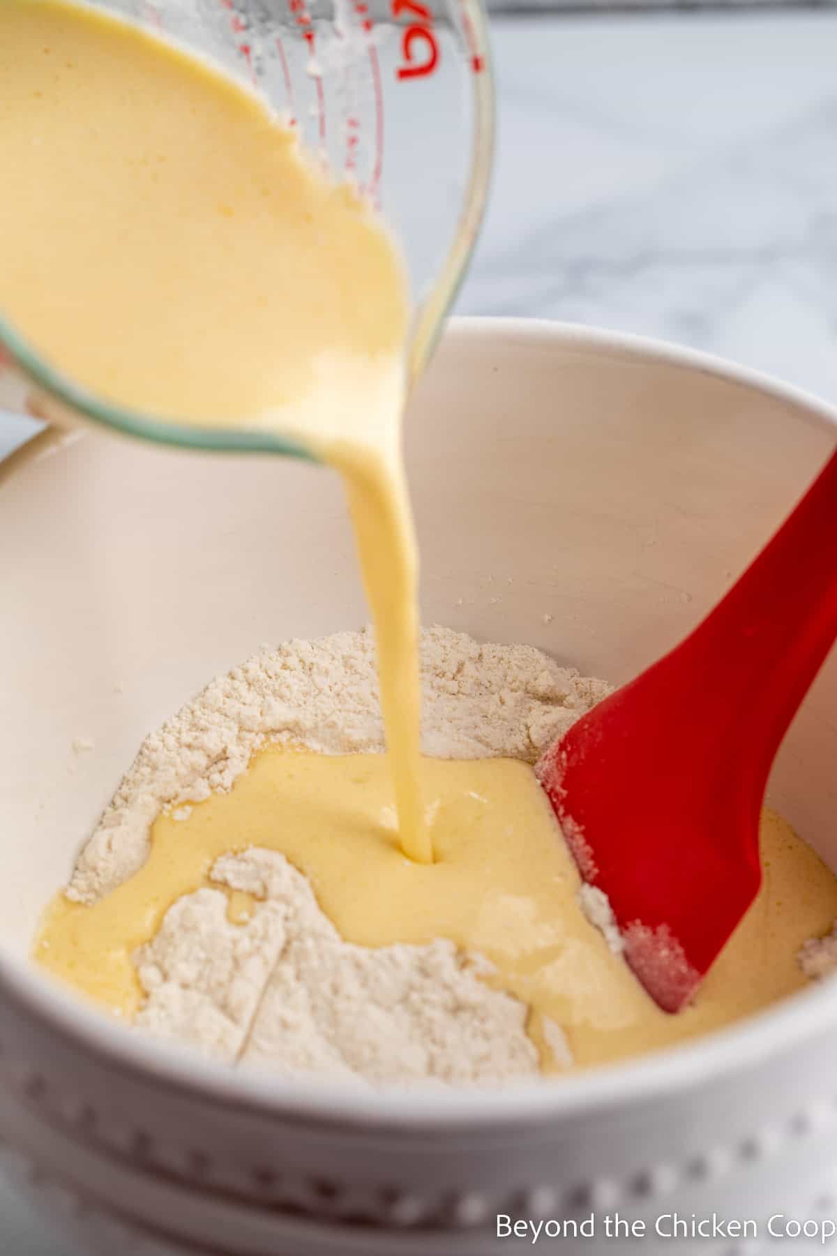 Pouring liquid into a bowl with flour. 