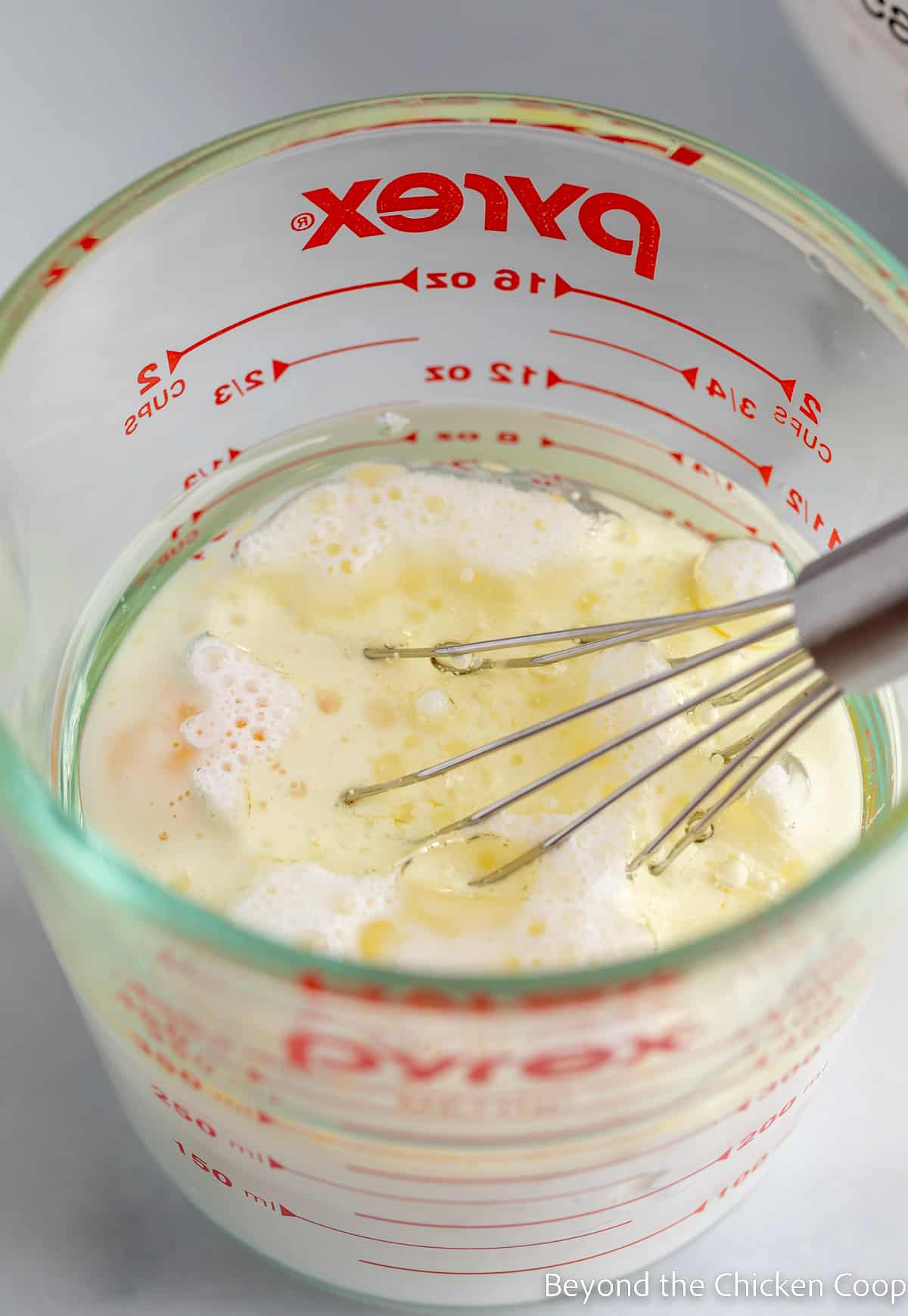 A measuring cup with milk and oil. 