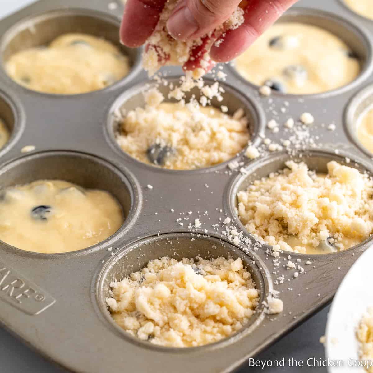 Sprinkling a topping over muffin batter. 