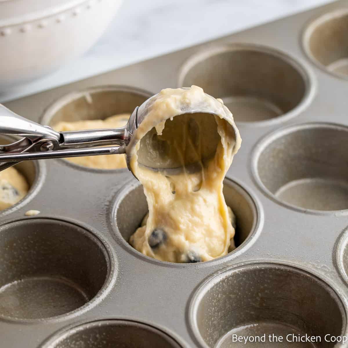 Scooping batter into a muffin tin. 