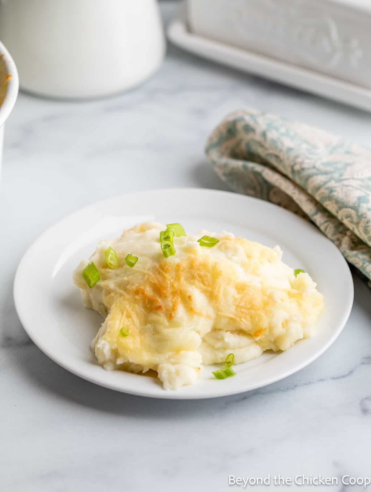 A portion of mashed potatoes on a small white plate. 