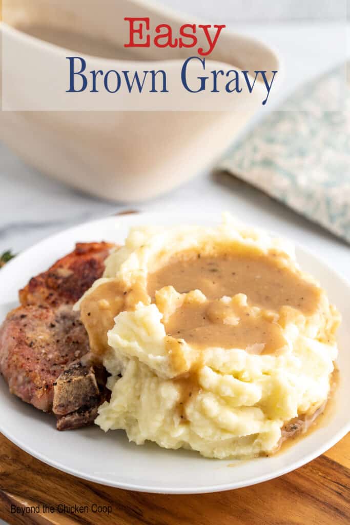 Mashed potatoes with gravy next to a pork chop on a plate.