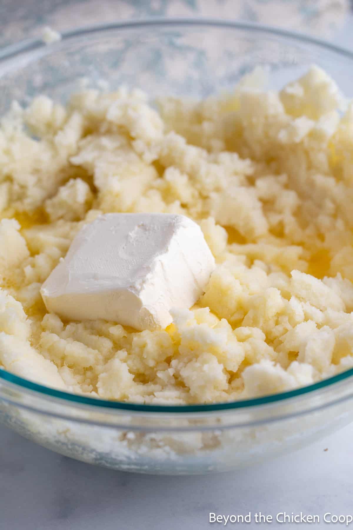 Adding cream cheese to mashed potatoes. 