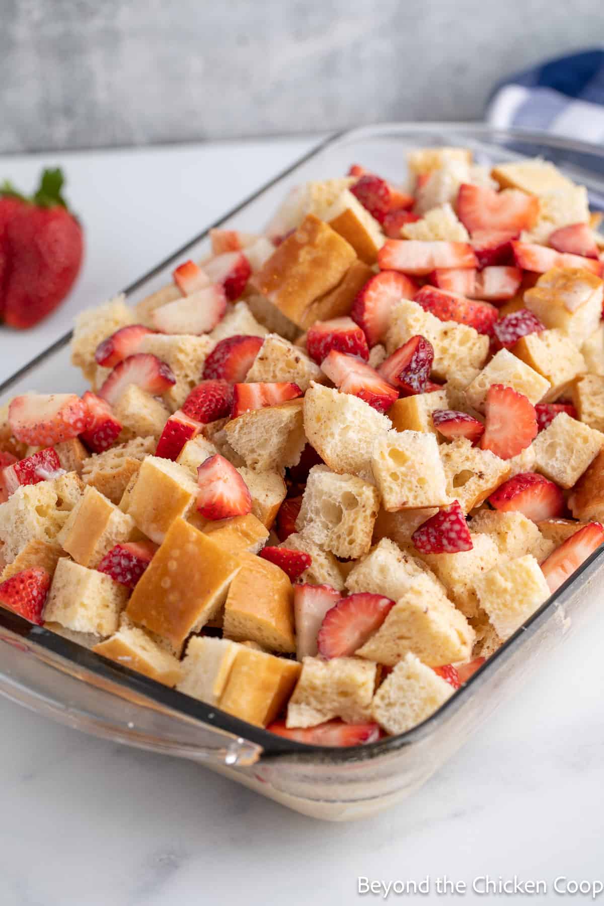 Bread cubes and strawberries in a baking dish.