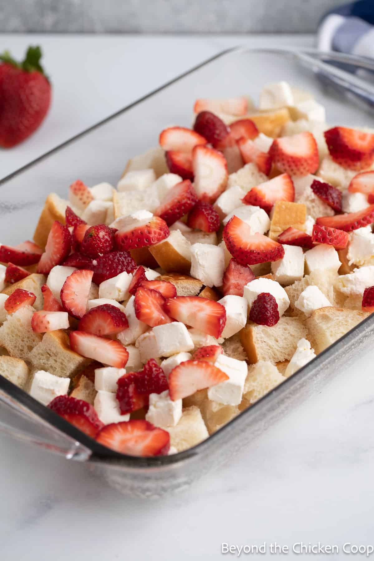 Layering bread and strawberries in a casserole dish. 