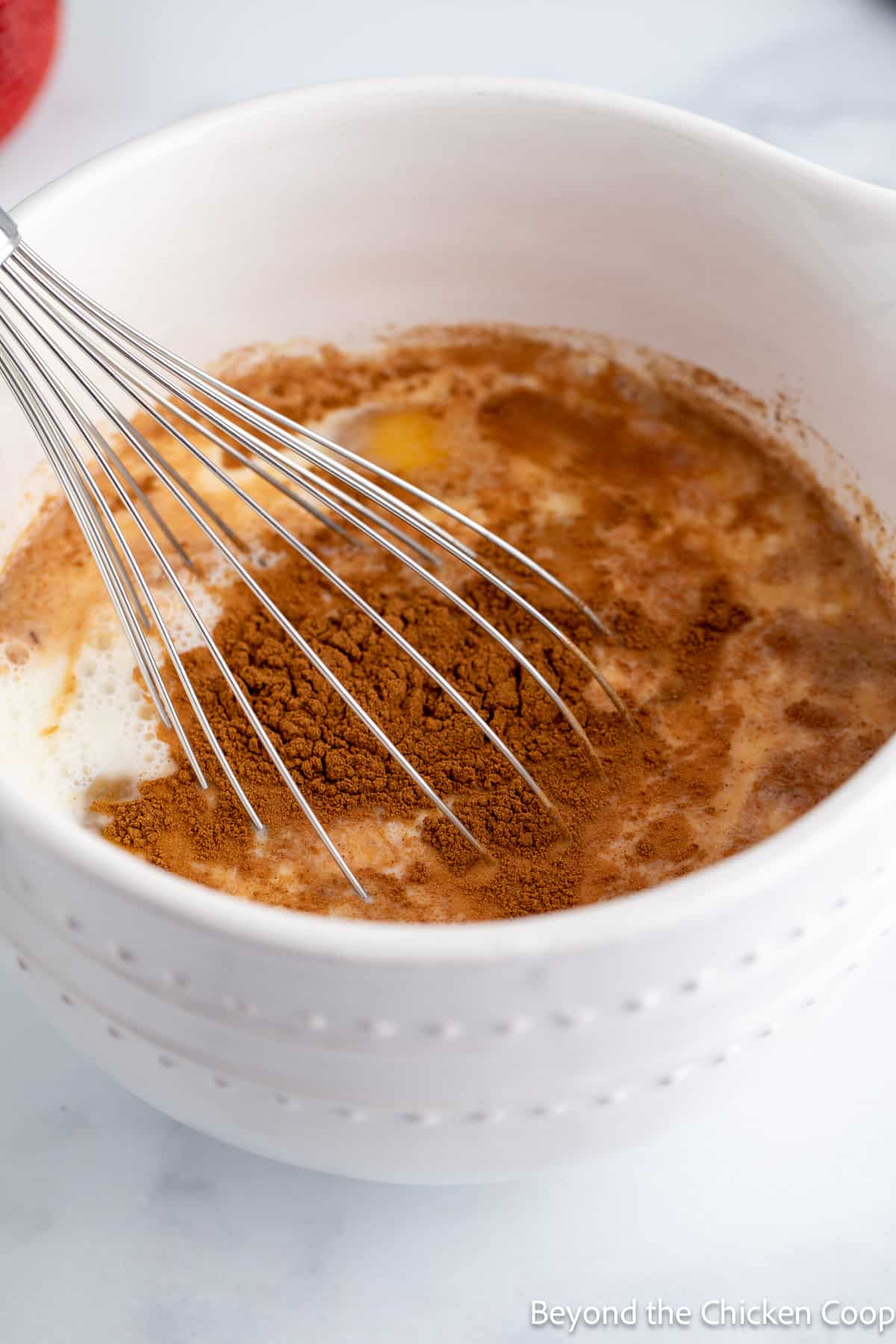 A bowl filled with eggs, milk and cinnamon.