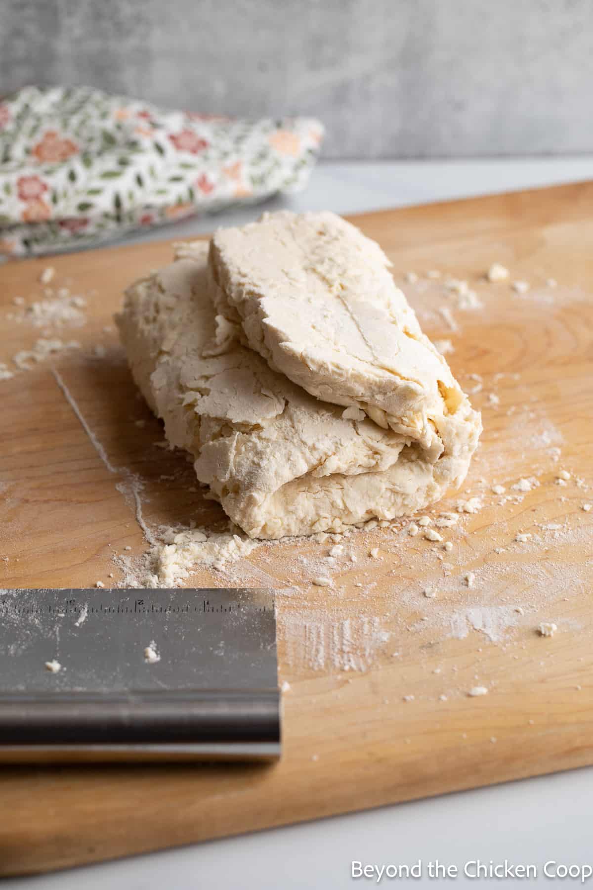 Folded biscuit dough on a wooden board. 