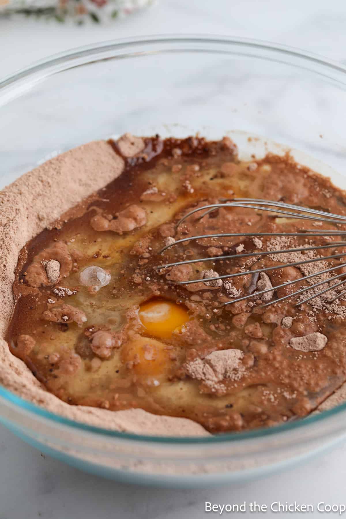 Mixing eggs and oil into a chocolate batter.