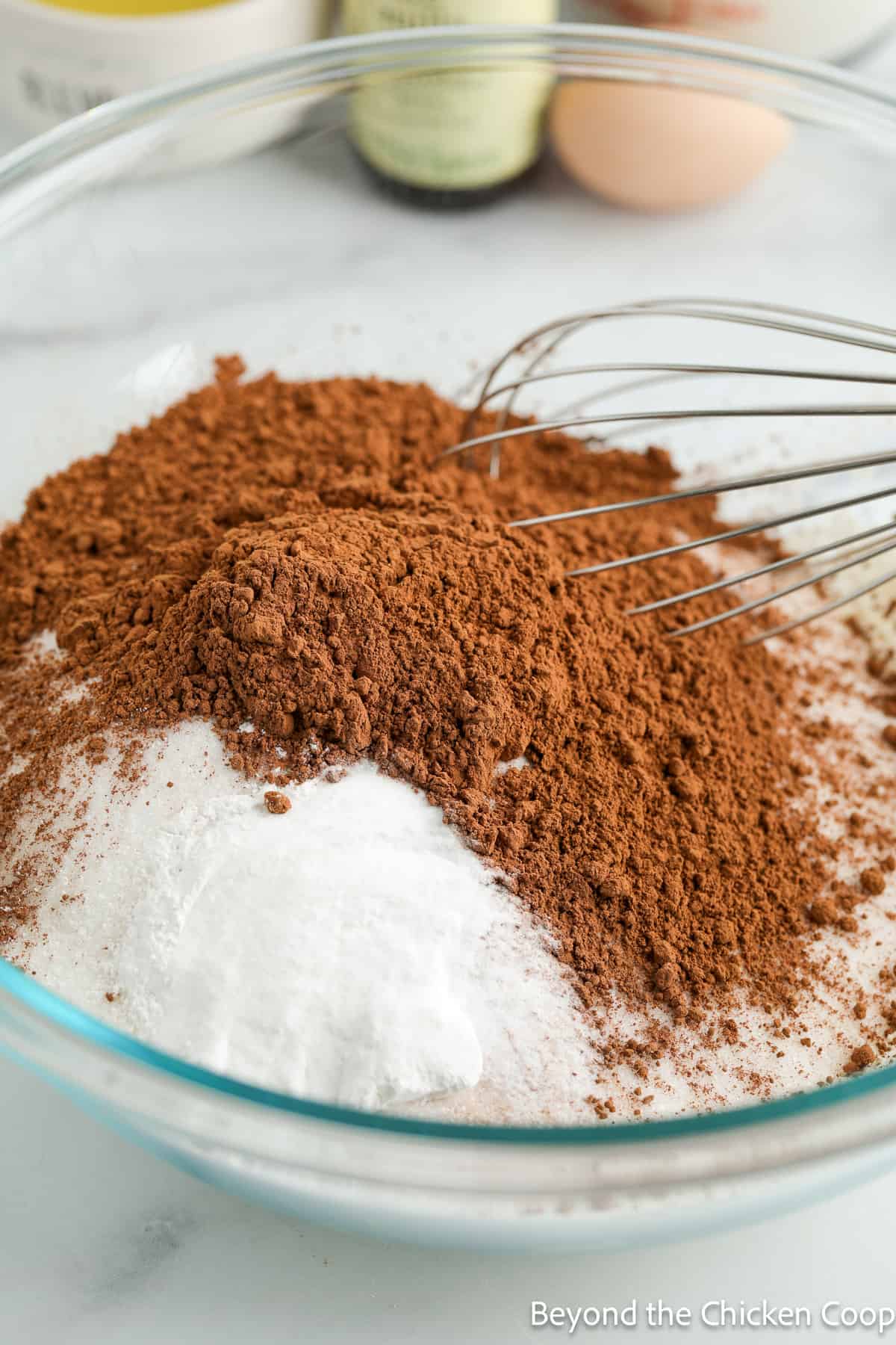 Flour and cocoa powder in a glass bowl with a whisk. 