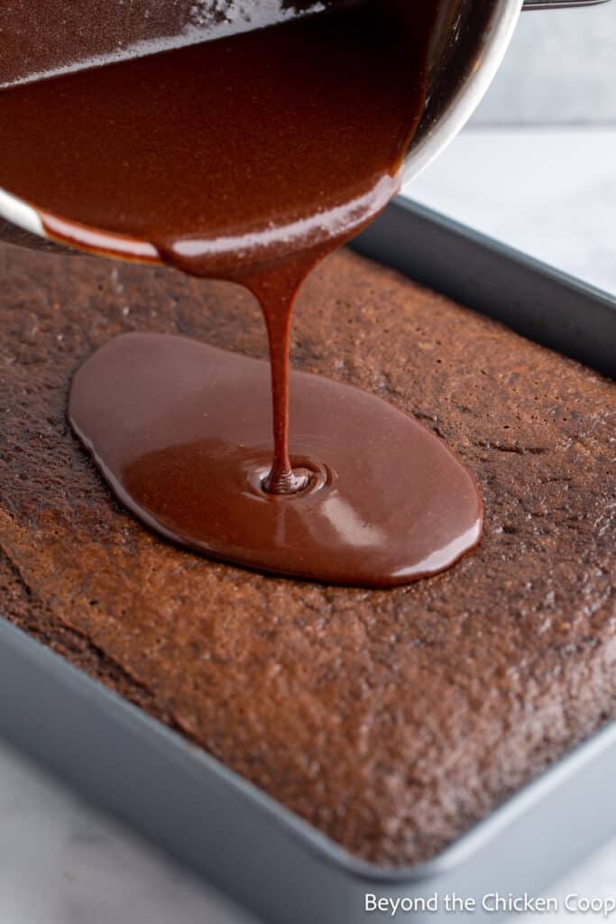 Pouring chocolate icing onto a chocolate cake. 