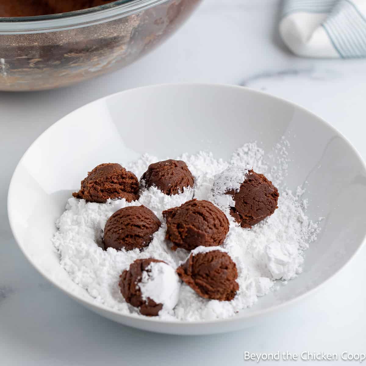 Chocolate dough in a bowl of powdered sugar. 
