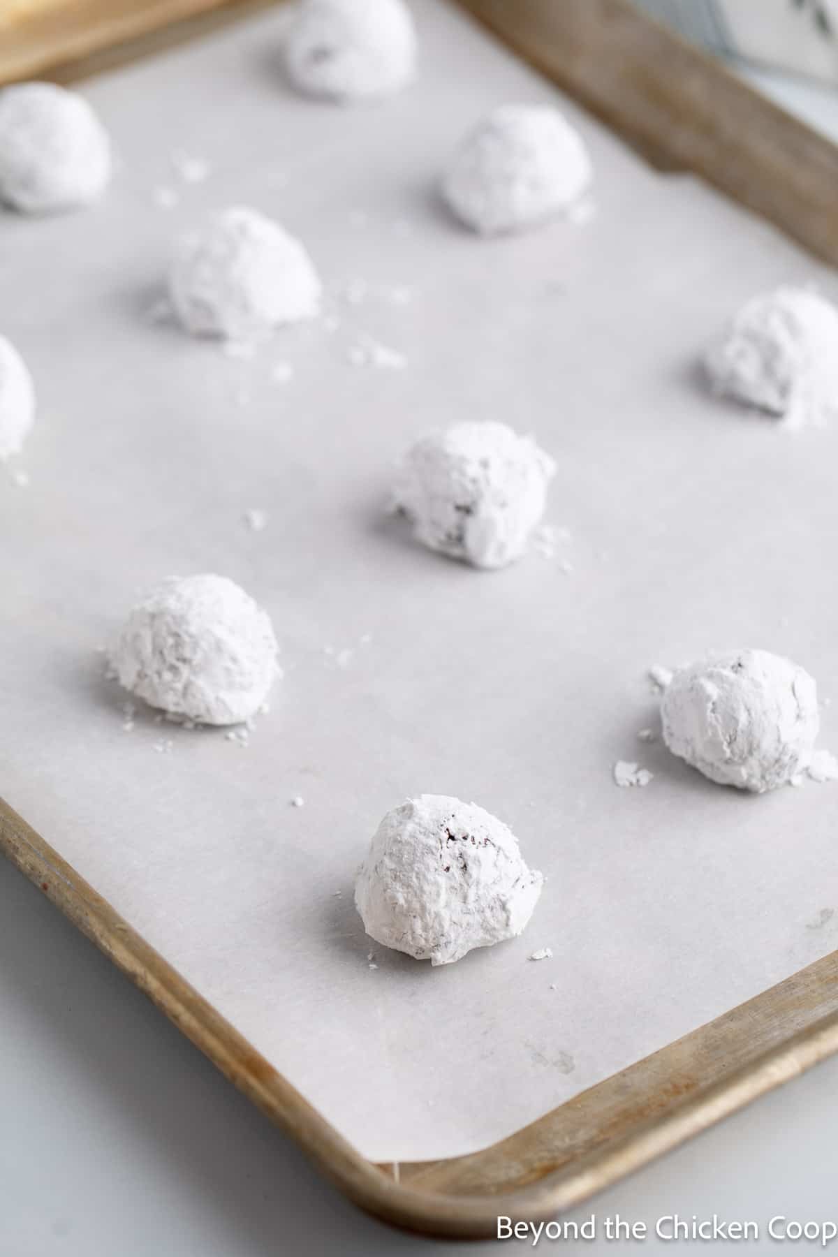 Unbaked chocolate crinkles on a baking sheet. 