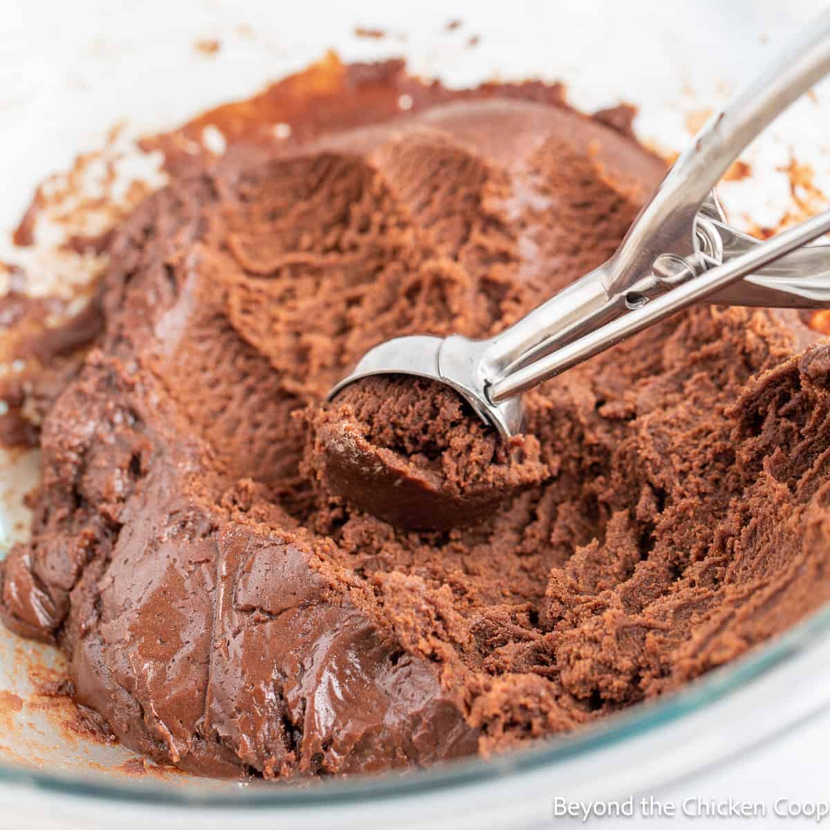 Scooping chocolate cookie dough with a small scoop. 