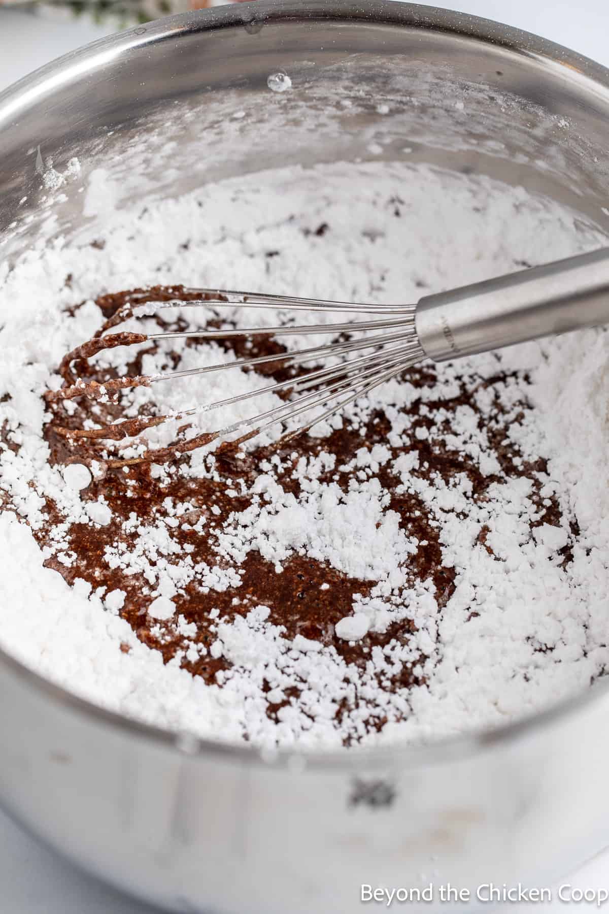 Mixing powdered sugar into butter and cocoa powder. 