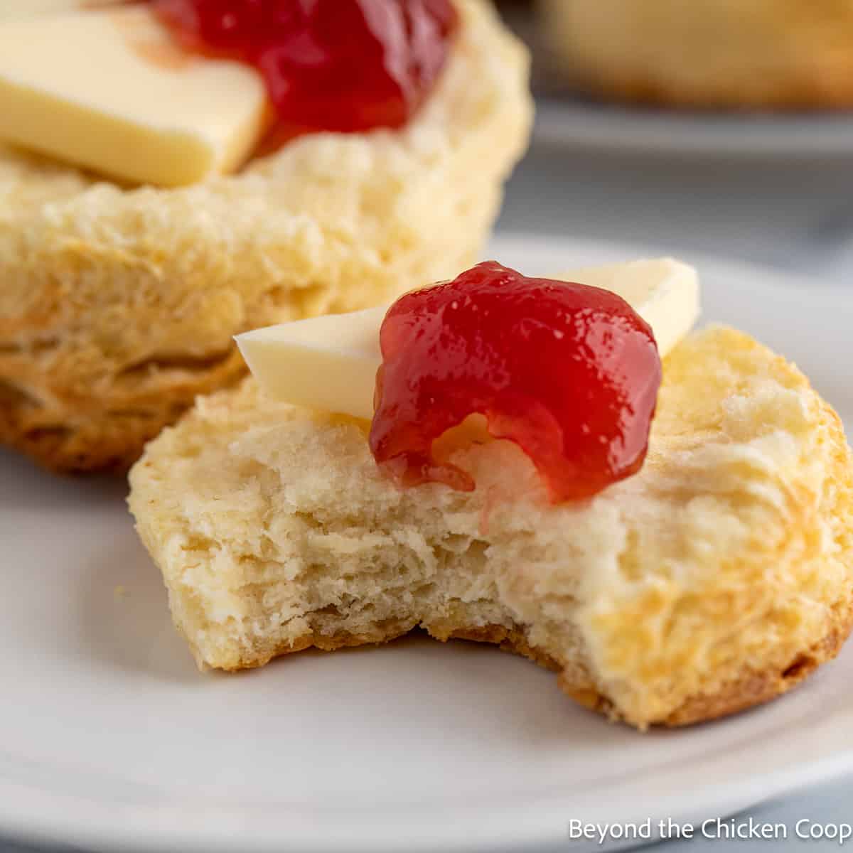 Half of a biscuit topped with butter and jam.