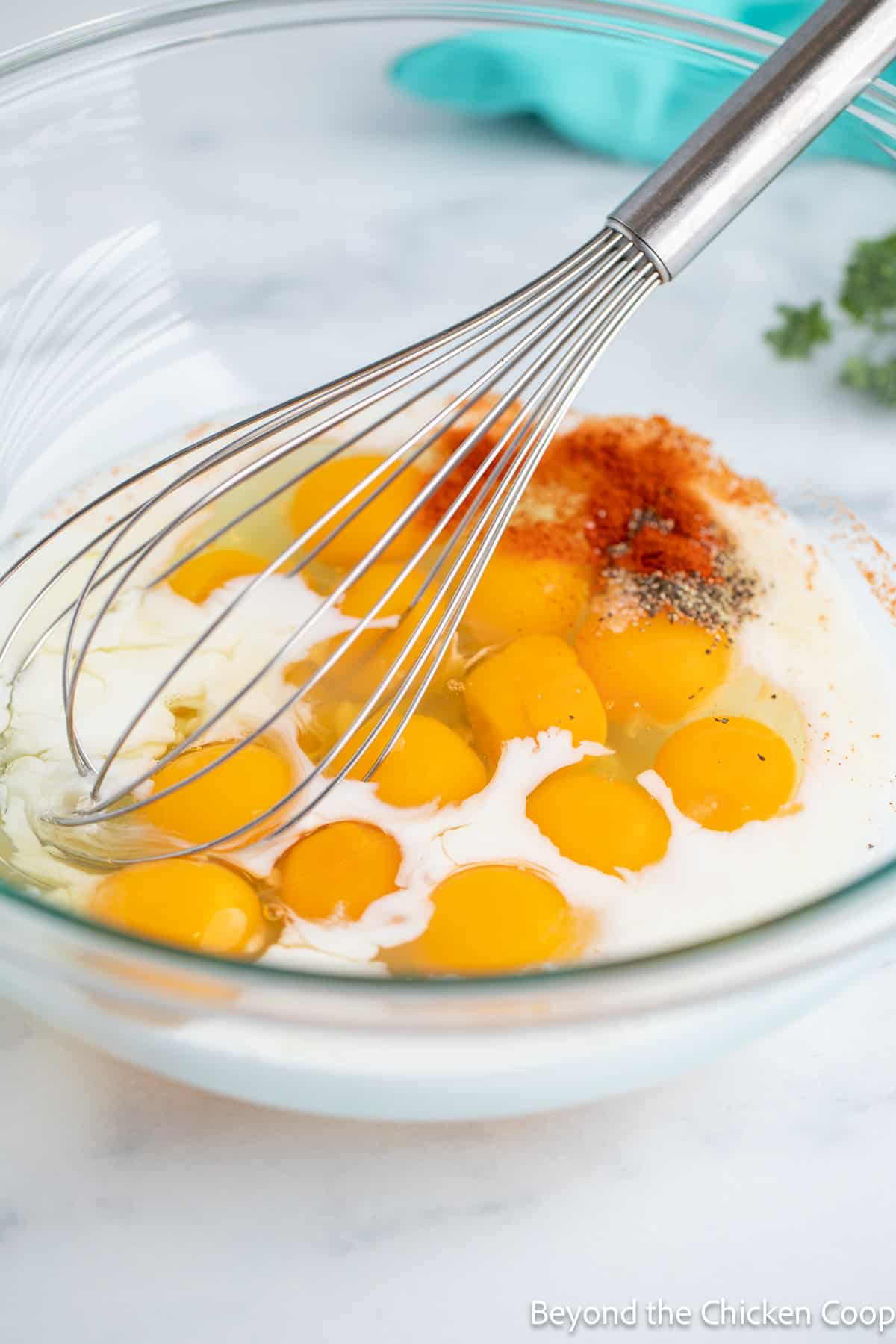 Eggs in a large bowl with milk and spices. 