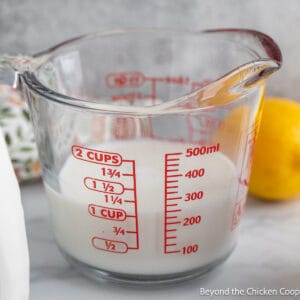 A glass measuring cup filled with milk.