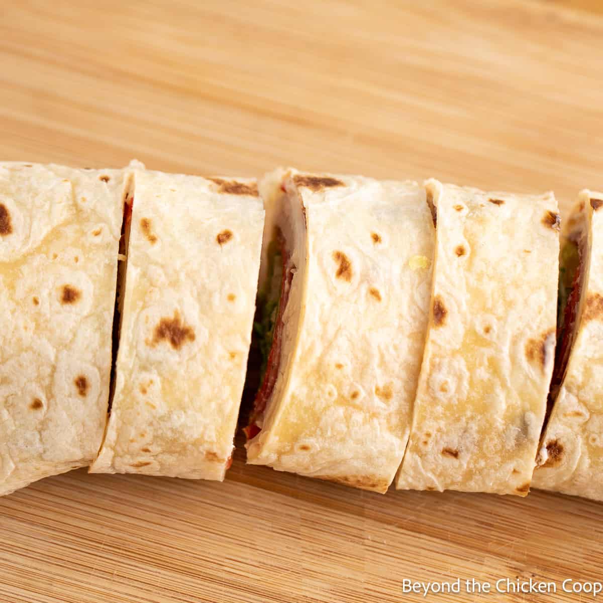 Sliced tortilla wrap on a wooden cutting board. 