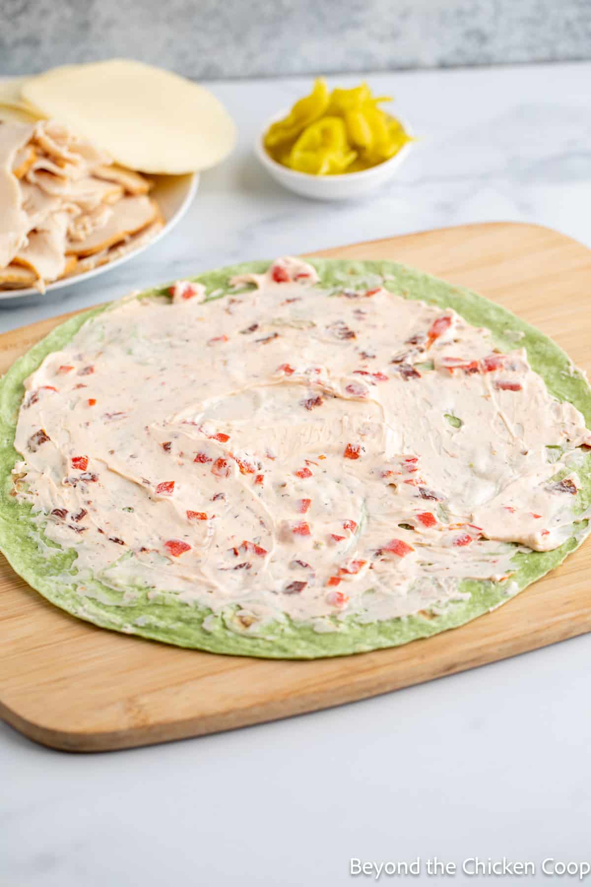 Cream cheese spread over a green tortilla wrap. 