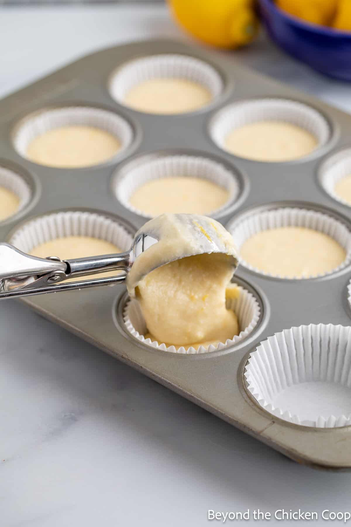 Scooping cake batter into a cupcake pan. 