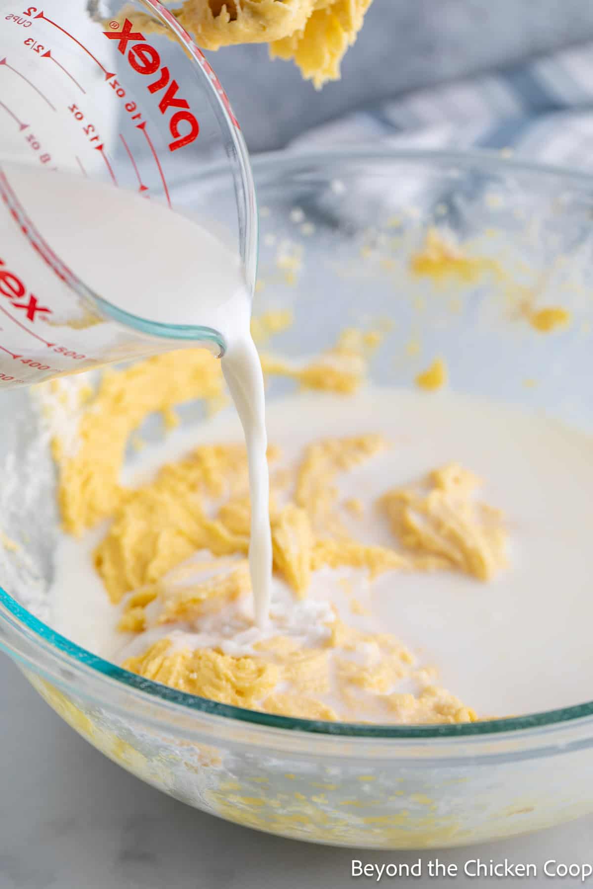 Pouring milk into cake batter. 