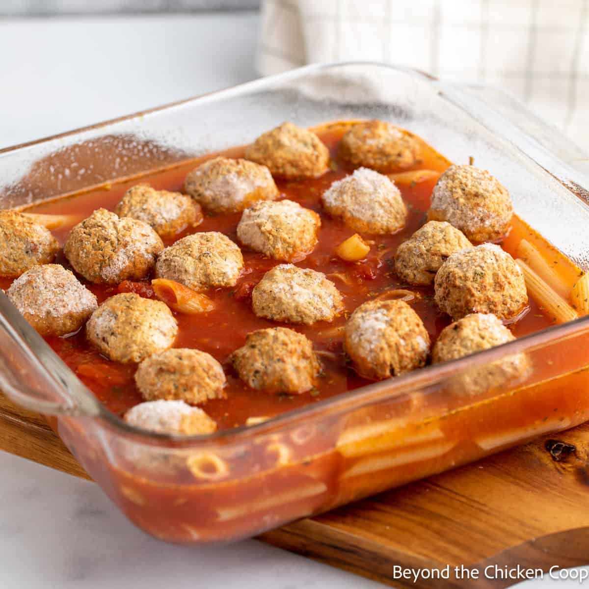 Frozen meatballs with sauce and pasta in a glass dish. 
