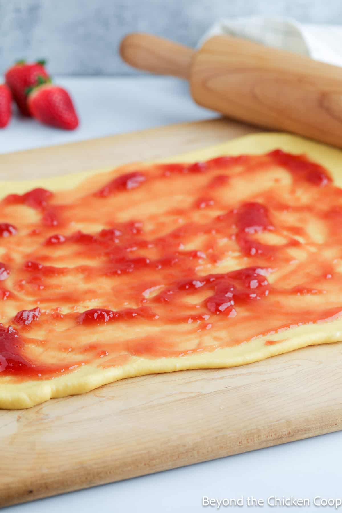 Strawberry jam spread on top of rolled dough.