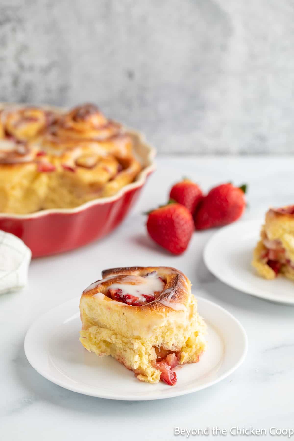 Cinnamon roll filled with strawberries on a small white plate. 