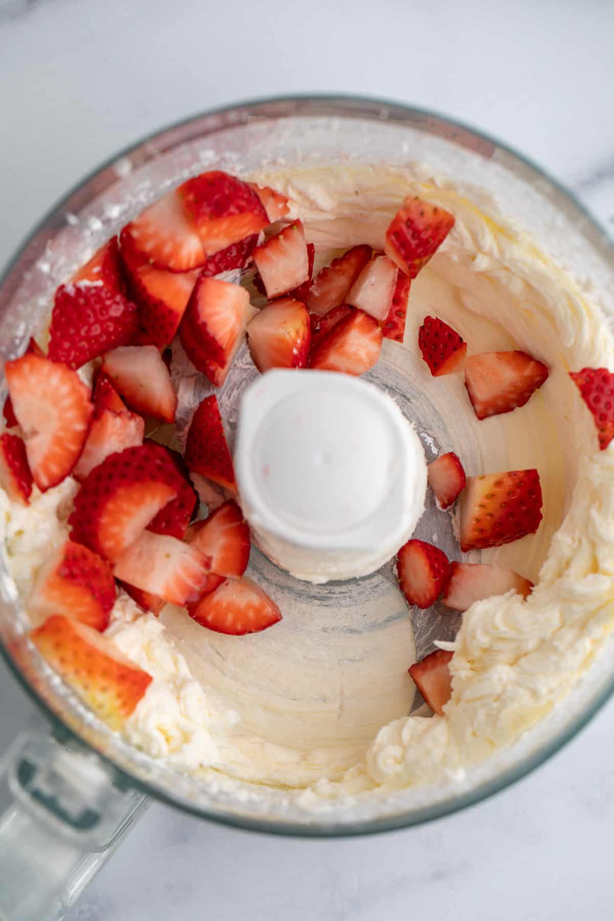 Chunks of strawberries in a food processor bowl. 