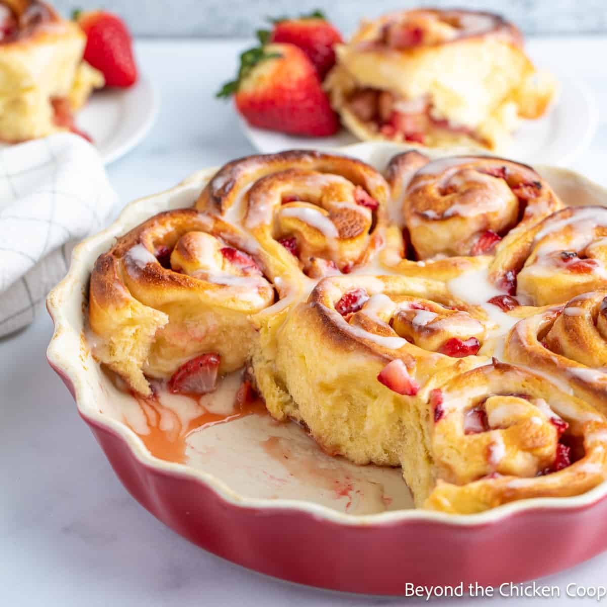 Cinnamon rolls filled with strawberries in a red dish.