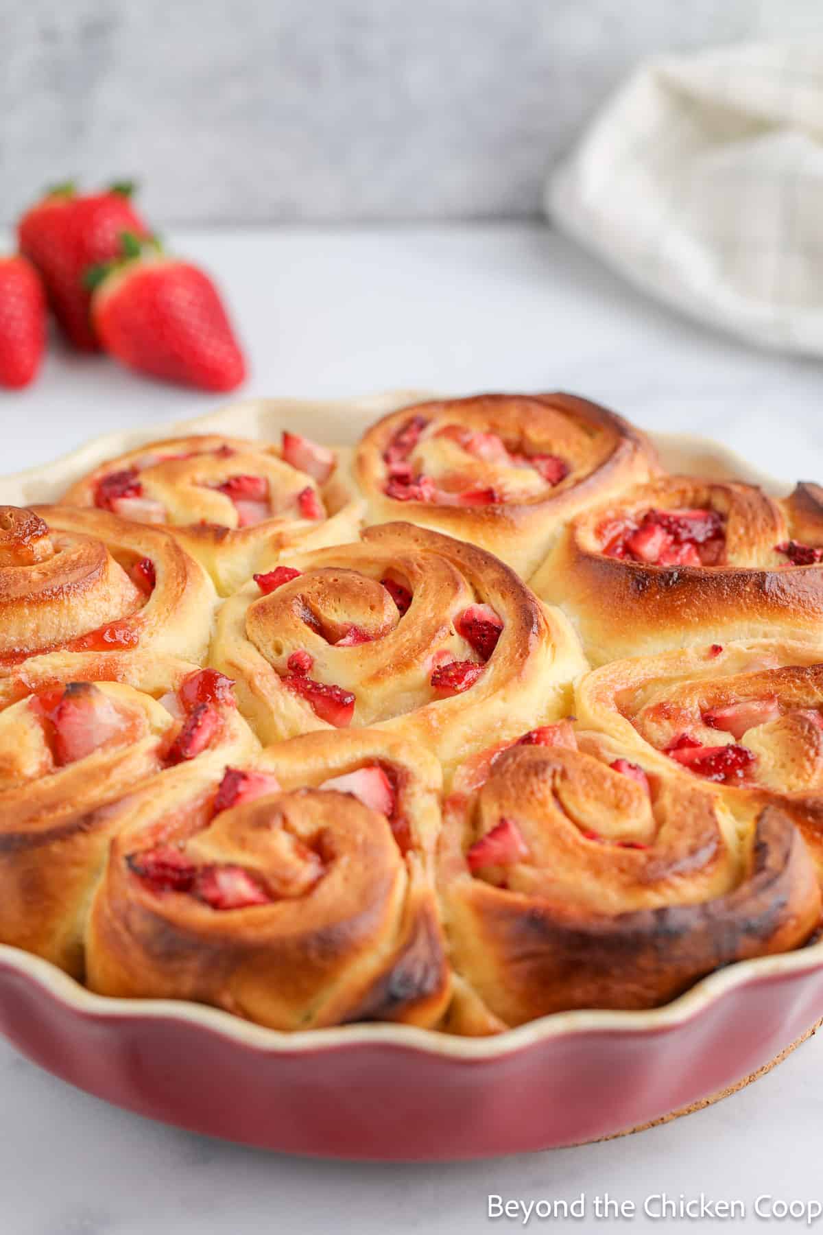 Baked cinnamon rolls with strawberries in a pan.