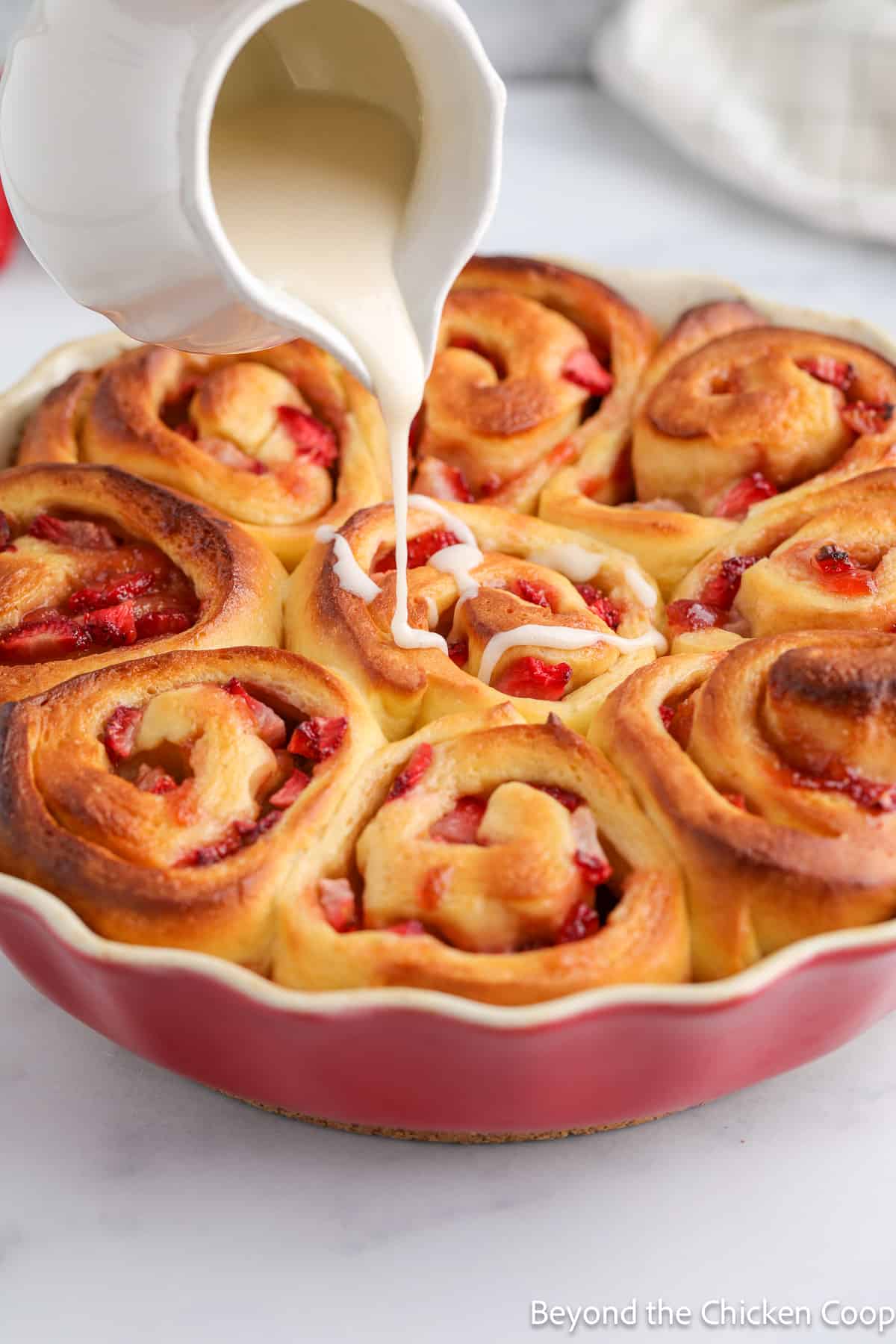 Pouring icing over sweet rolls.