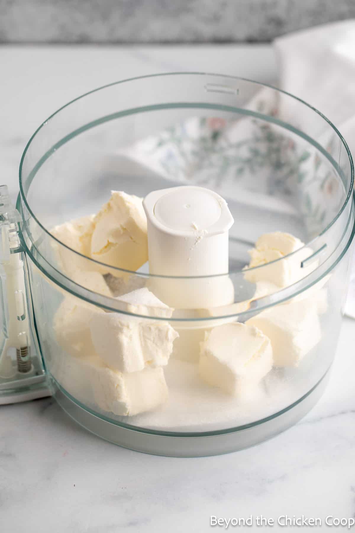 Chunks of cream cheese in a food processor. 