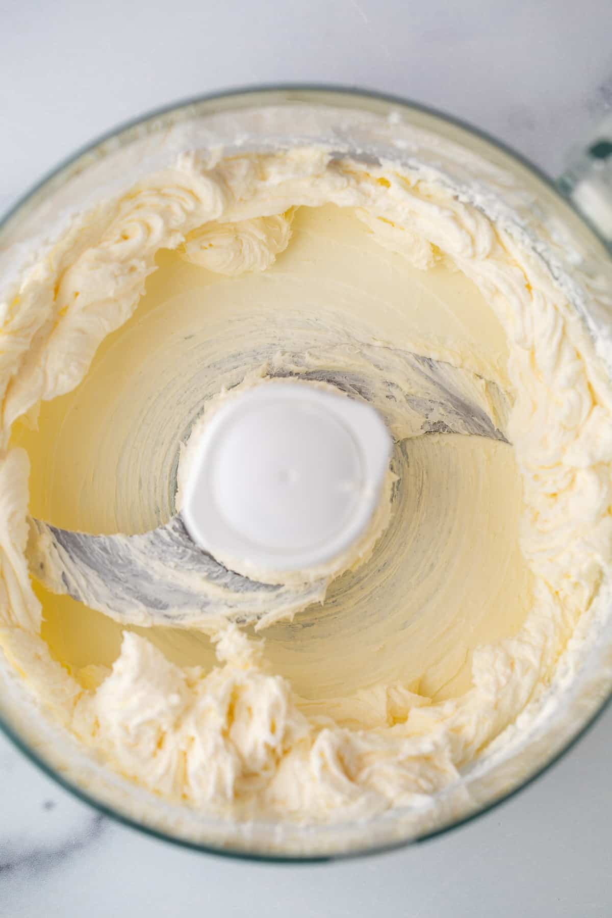 Blended cream cheese in a food processor bowl.