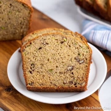Slices of banana bread with zucchini and pecans on a white plate.